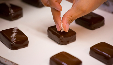A photo of salt being meticulously applied to a piece of John Kelly Chocolate.