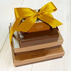 Four boxes stacked vertically from largest to smallest. They are tied together with a golden ribbon.