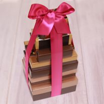 Eight boxes stacked vertically from largest to smallest. They are tied together with a fuchsia ribbon.